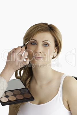 Make-up artist applying make up to a blond-haired female