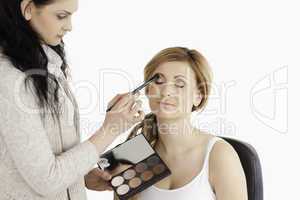 Young woman having her make up done by a make up artist