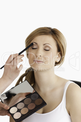 Make-up artist applying make up to a young woman in a studio