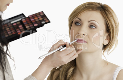 Cute woman having her make up done by a make up artist