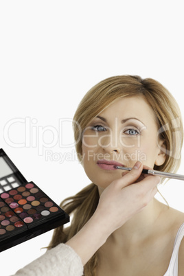 Young blond-haired woman having her make up done by a make up ar