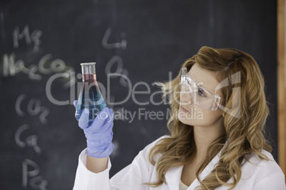 Young scientist looking at a red and blue flask