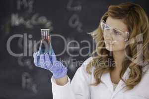 Young female scientist looking at a red and blue flask