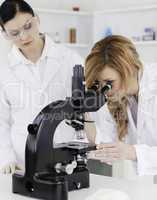 Blond-haired scientist looking through a microscope with her ass