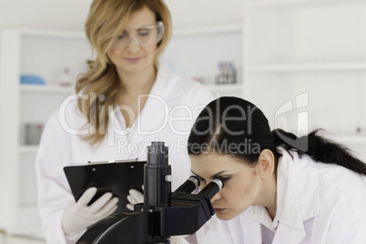 Dark-haired scientist and her assistant conducting an experiment