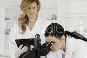 Dark-haired scientist and her assistant conducting an experiment