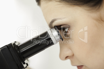 Dark-haired scientist looking through a microscope