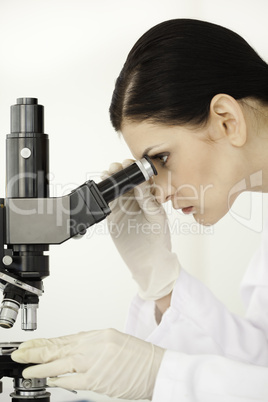Scientist conducting an experiment looking through a microscope