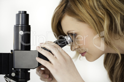 Blond-haired scientist looking through a microscope in a lab