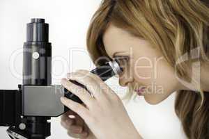 Blond-haired scientist looking through a microscope in a lab