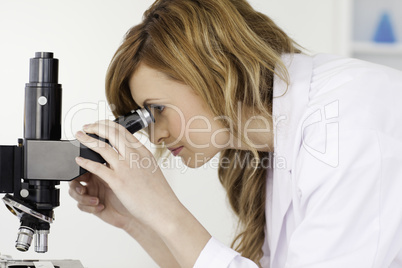 Attractive blond-haired scientist looking through a microscope