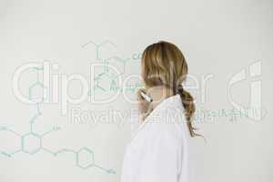 Blond-haired scientist writing a formula on a white board