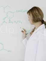 Cute female scientist writing a formula on a white board