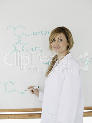 Cute scientist looking at the camera while standing near a white