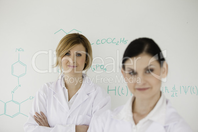 Two women posing in front of a white board