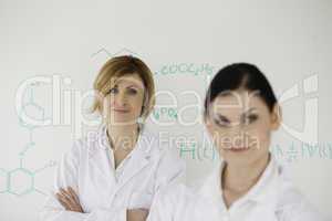 Two women posing in front of a white board