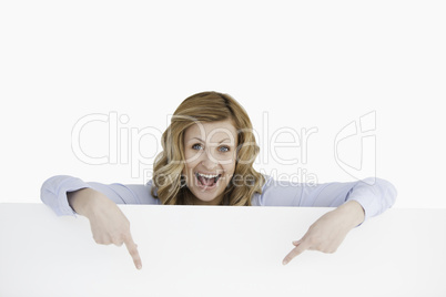 Happy blond-haired woman standing behind an empty white board