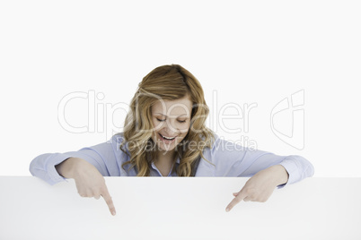 Smiling blond-haired woman standing behind an empty white board
