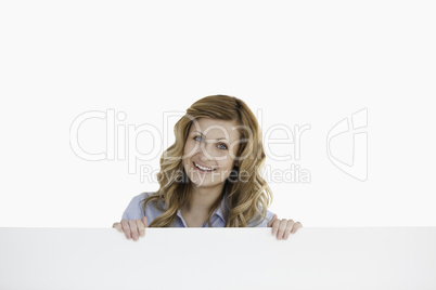 Lovely blond-haired woman standing behind an empty white board