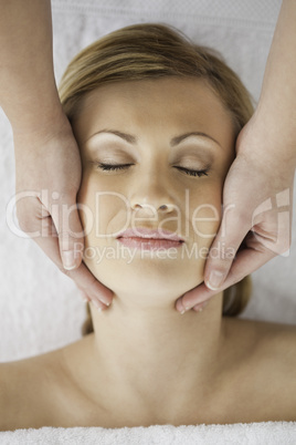 Beautiful blond-haired woman getting a massage on her face