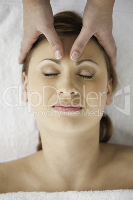 Cute blond-haired woman getting a massage on her face