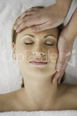 Lovely blond-haired woman getting a massage on her face