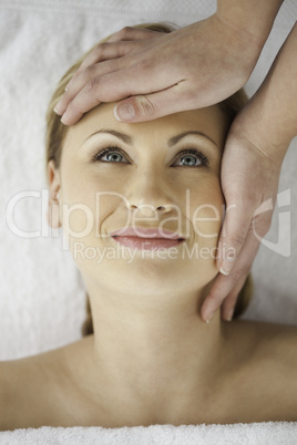 Pretty blond-haired woman getting a massage on her face