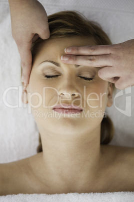 Young blond-haired woman getting a massage on her face