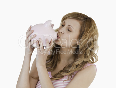 Blond-haired woman kissing her piggybank