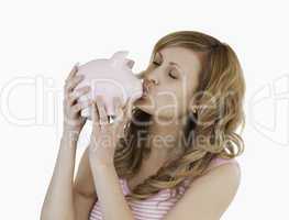 Blond-haired woman kissing her piggybank