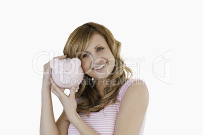 Cute woman smiling while holding her piggybank