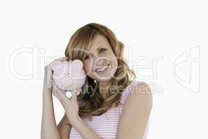 Cute woman smiling while holding her piggybank