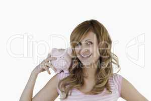 Blond-haired woman posing while holding her piggybank