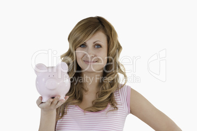 Cute blond-haired woman posing while holding her piggybank