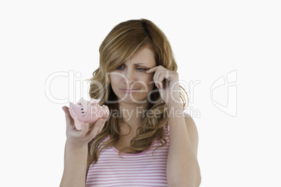 Blond-haired woman crying while holding her broken piggybank