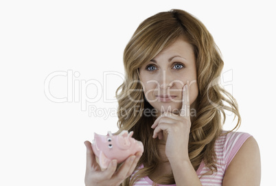 Blond-haired woman thoughtful while holding her broken piggybank