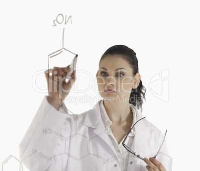 Dark-haired woman writting a formula on a white board