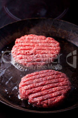 zwei Rindfleisch Bratlinge in einer Eisenpfanne