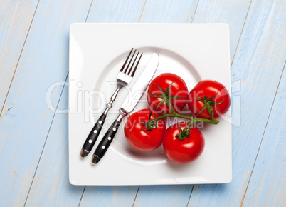 vier Tomaten auf einem weißen Teller
