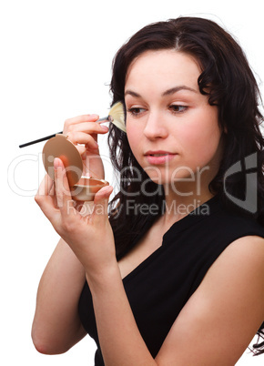Girl is applying rouge while looking at mirror