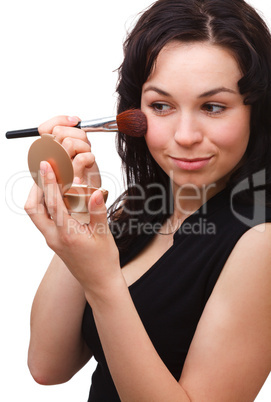 Girl is applying rouge while looking at mirror