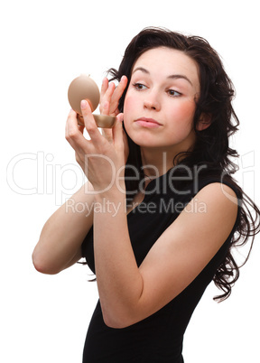 Girl is applying makeup while looking at mirror