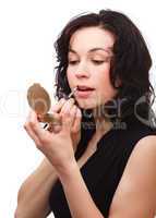 Woman is applying lipgloss while looking in mirror