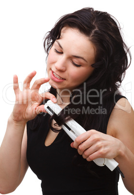 Woman is using hair straightener