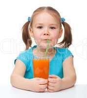 Little girl drinks orange juice