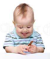 Cute little boy is holding chocolate bar and smile