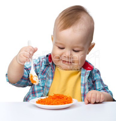 Cute little boy is playing with carrot salad