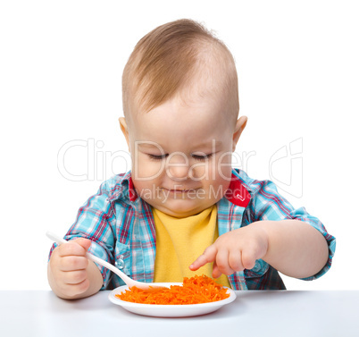 Cute little boy is playing with carrot salad