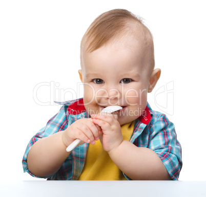 Cute little boy is biting spoon