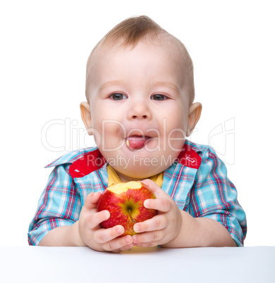 Little child is eating red apple